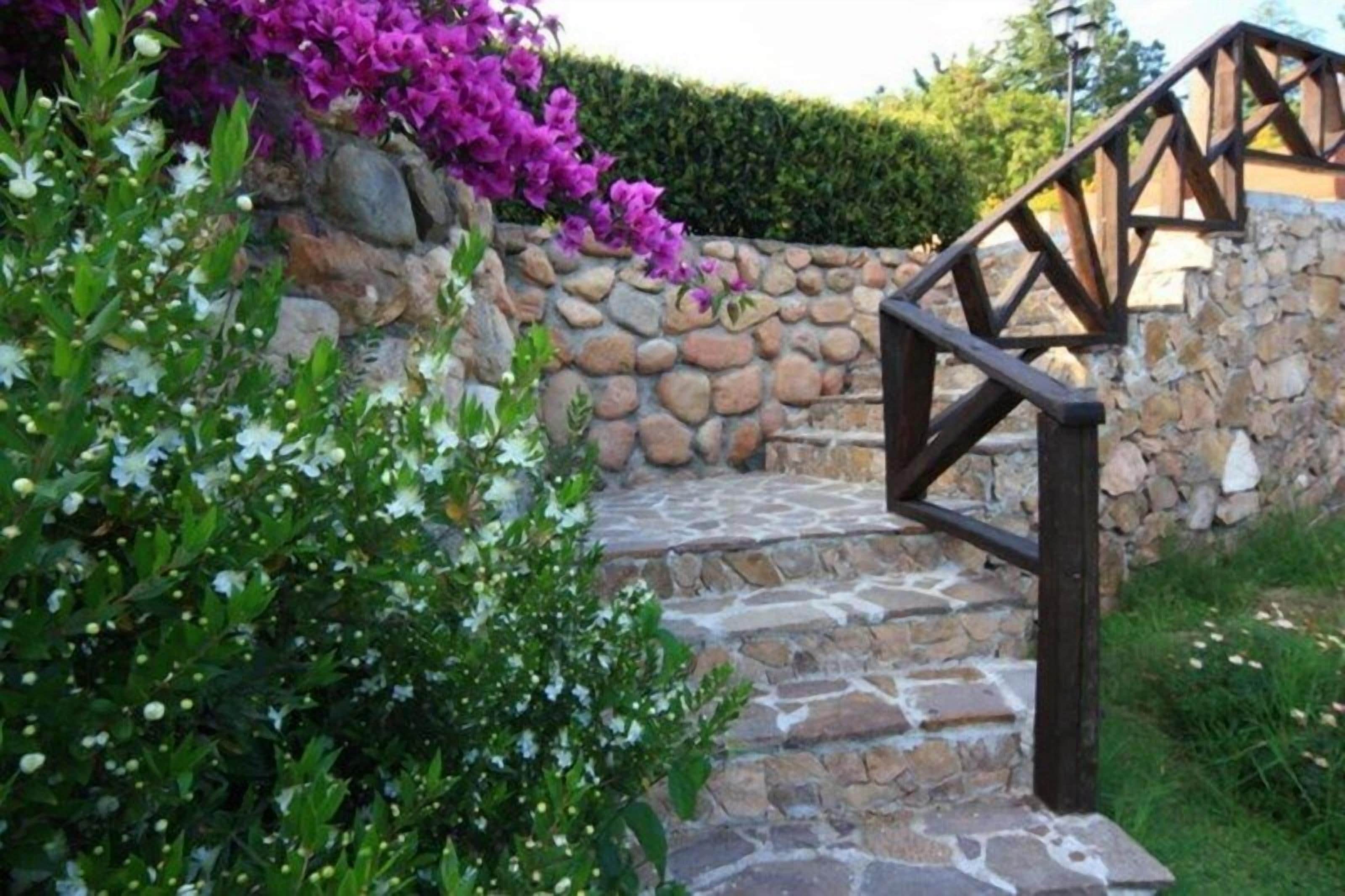 A stone staircase with a wooden handrail leading to a stone wall.
