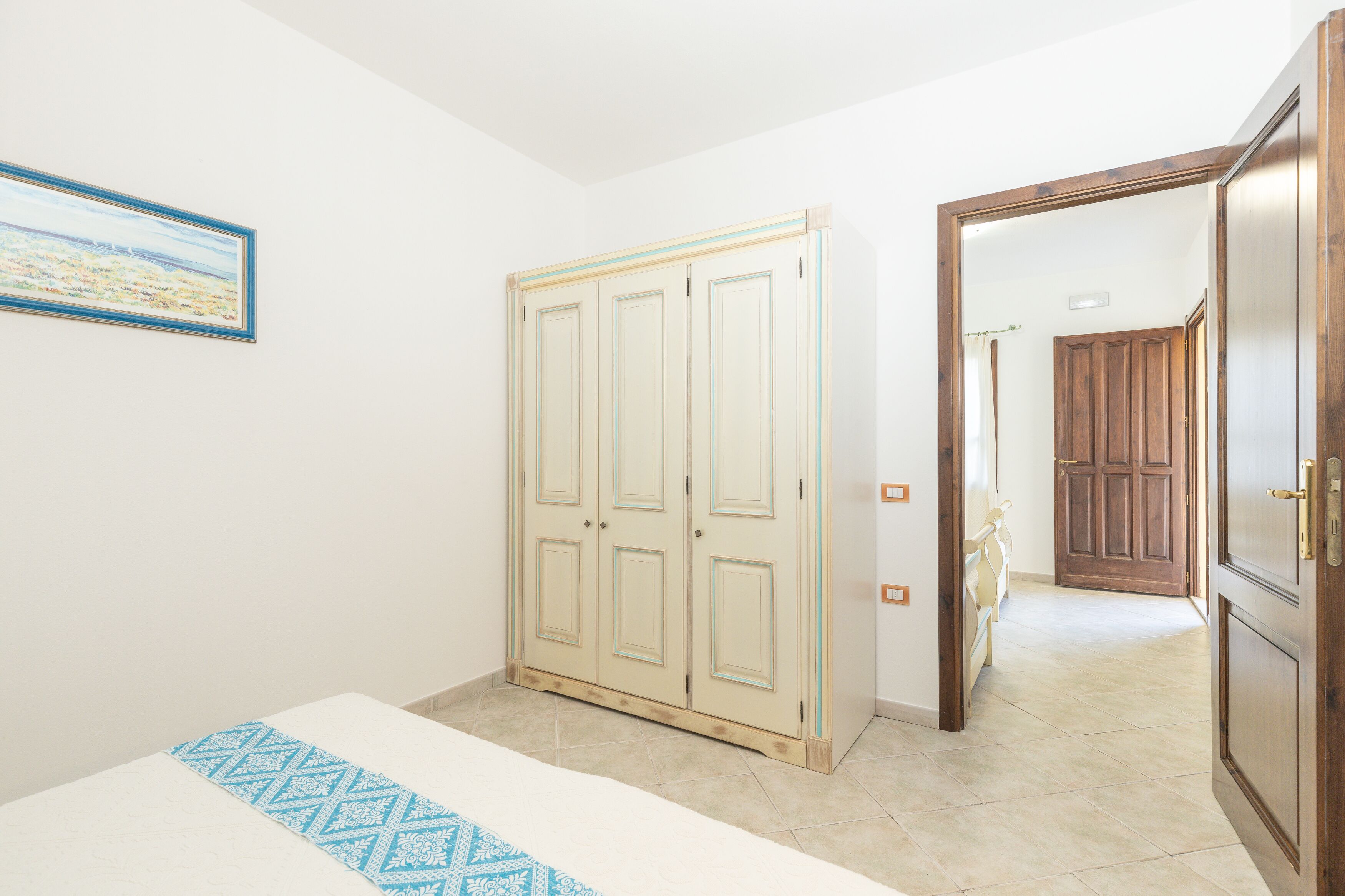 Un dormitorio con cama, armario y puerta que da a otra habitación.