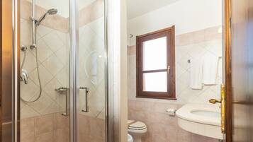 Ein Badezimmer mit Duschkabine aus Glas, Toilette und Waschbecken.