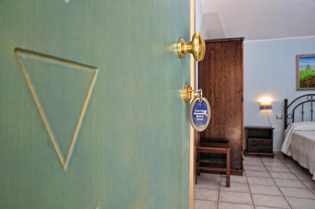 Una habitación con una cama, una puerta de madera y una mesita.