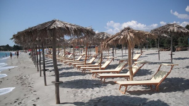 A beach with rows of sun loungers and thatched umbrellas. - Resort Baia Cea (Bari Sardo)
