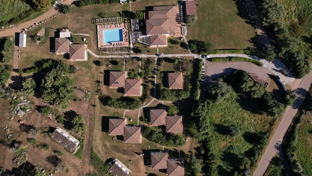 Vue aérienne d’un quartier résidentiel avec plusieurs maisons, une piscine et une allée incurvée.