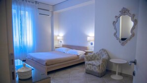 Una habitación de hotel con cama, una silla, una mesita y un espejo en la pared.