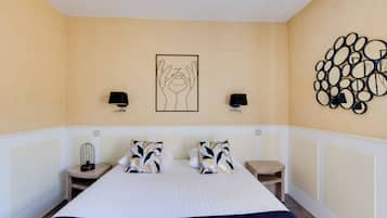 A hotel room with a large bed, two bedside tables, a wall art piece, and a decorative wall panel.