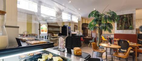A restaurant interior with a buffet area, seating, and a large indoor plant.