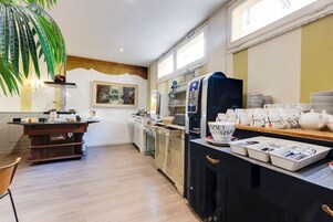 Una cocina moderna con cafetera, refrigerador y comedor con una mesa lista para dos.