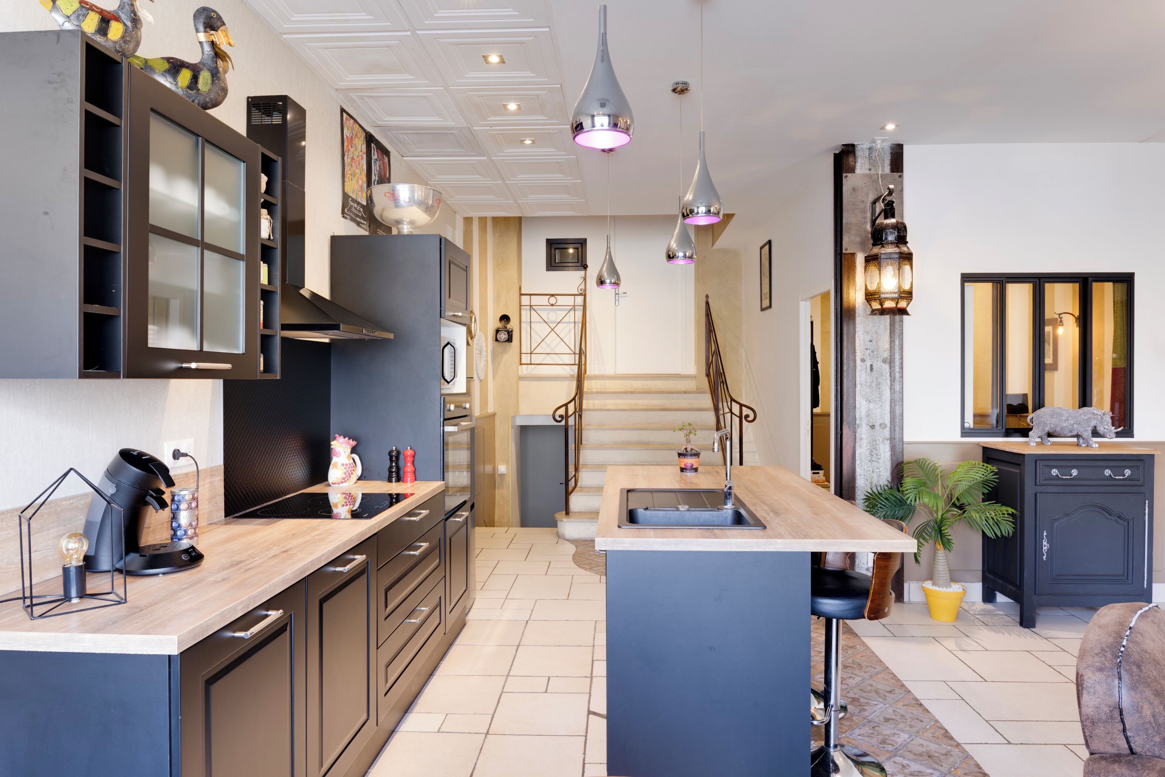 Una cocina moderna con una isla central, electrodomésticos integrados e iluminación colgante.