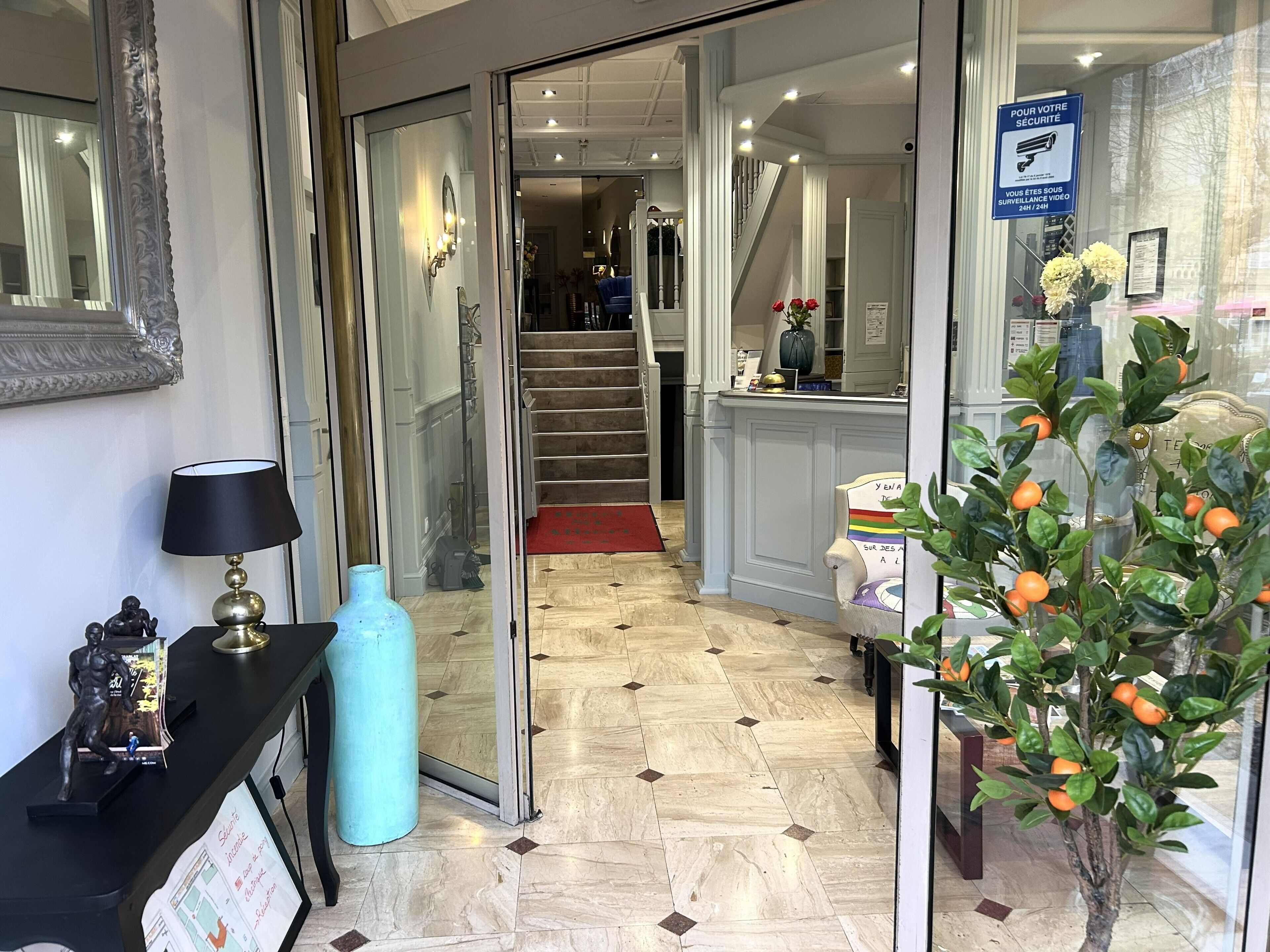 Un hall d’hôtel avec un comptoir d’accueil, un escalier et une plante en pot.