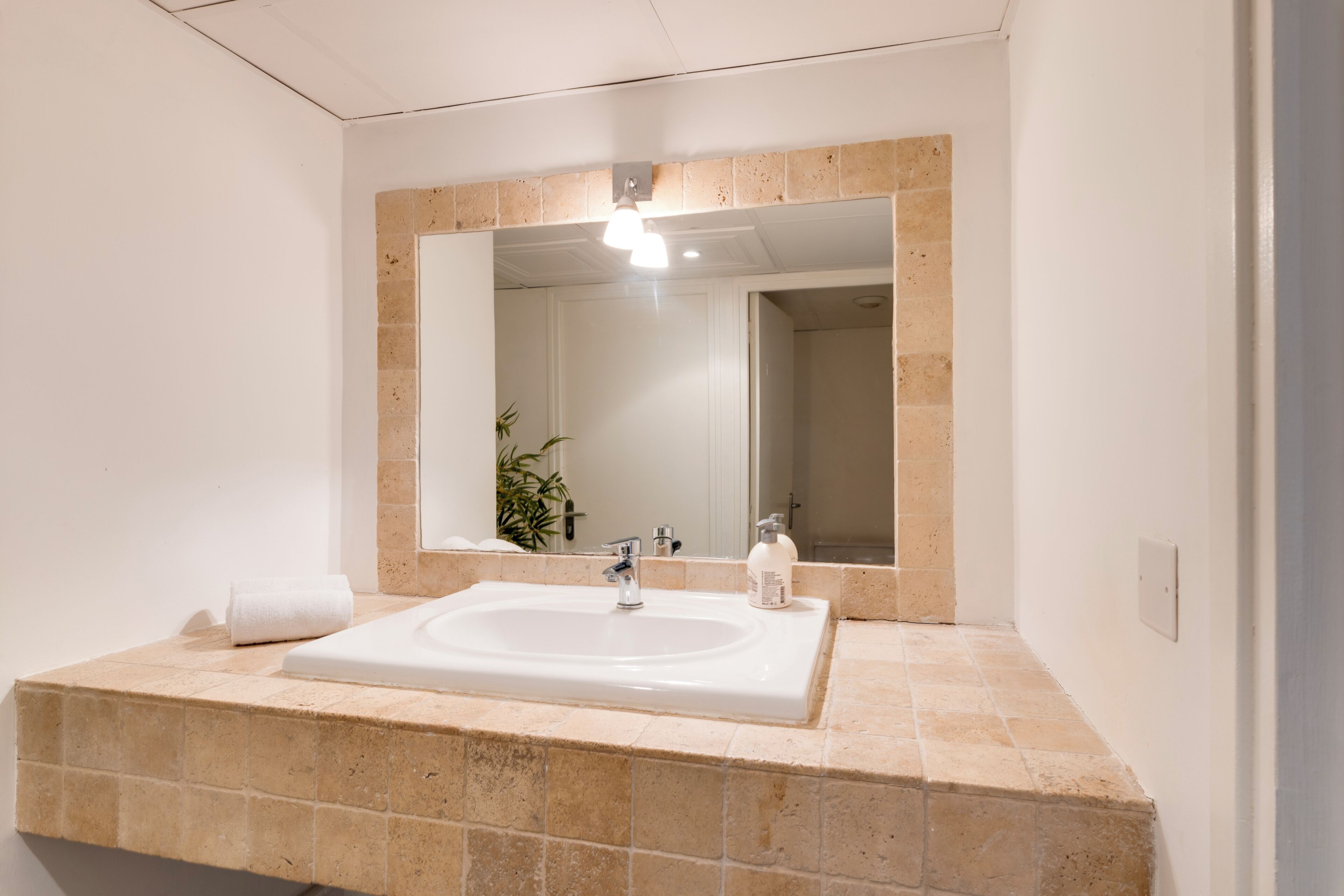 A bathroom with a large sink, a mirror, and a towel.