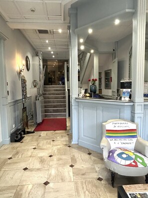 Vestíbulo de hotel con una escalera, una recepción y una silla de diseño llamativo.