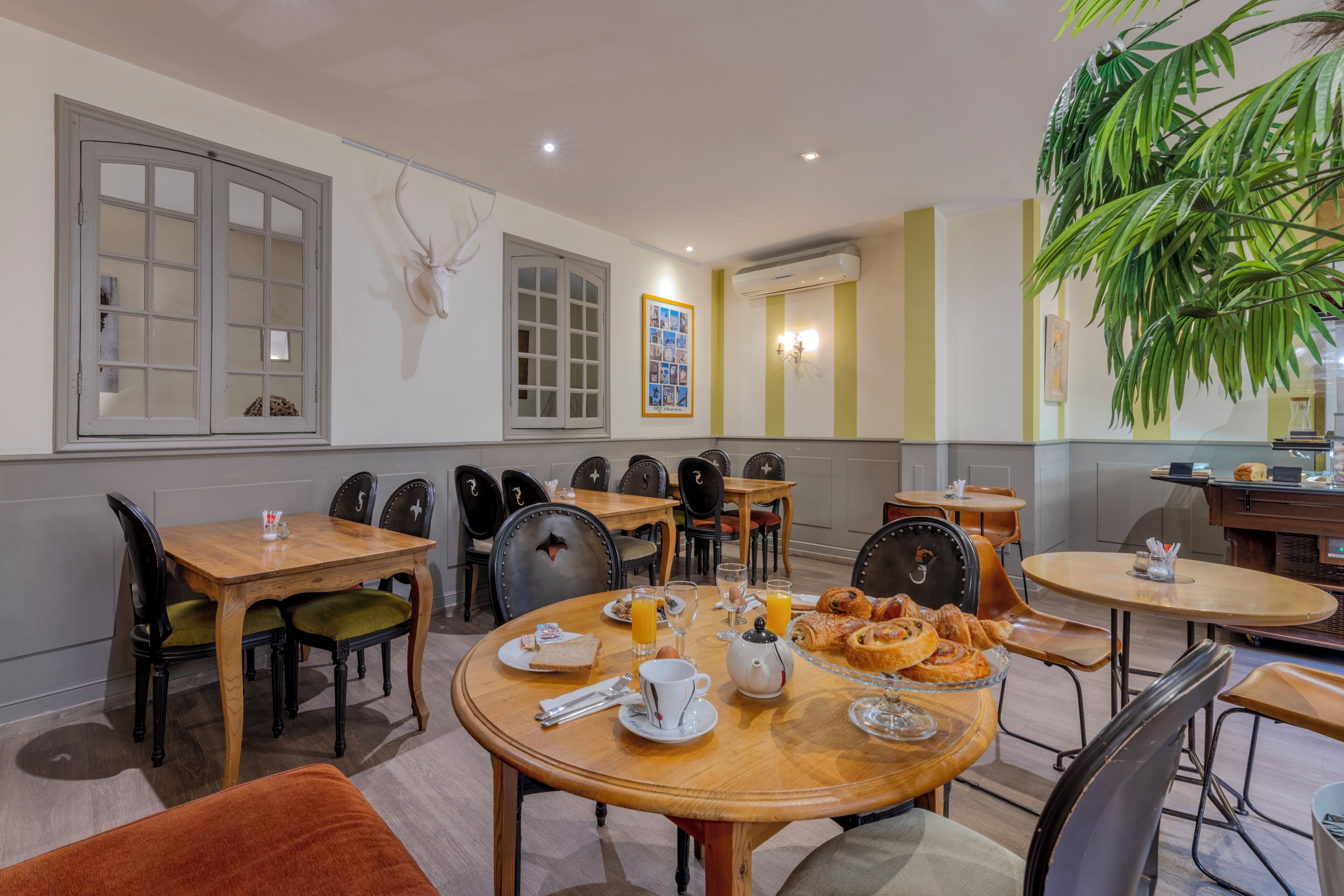 Un espace repas avec plusieurs tables et chaises, une horloge murale et un tableau encadré.