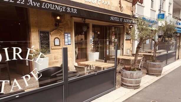 Un bar salón con mesas al aire libre y vistas a la calle.