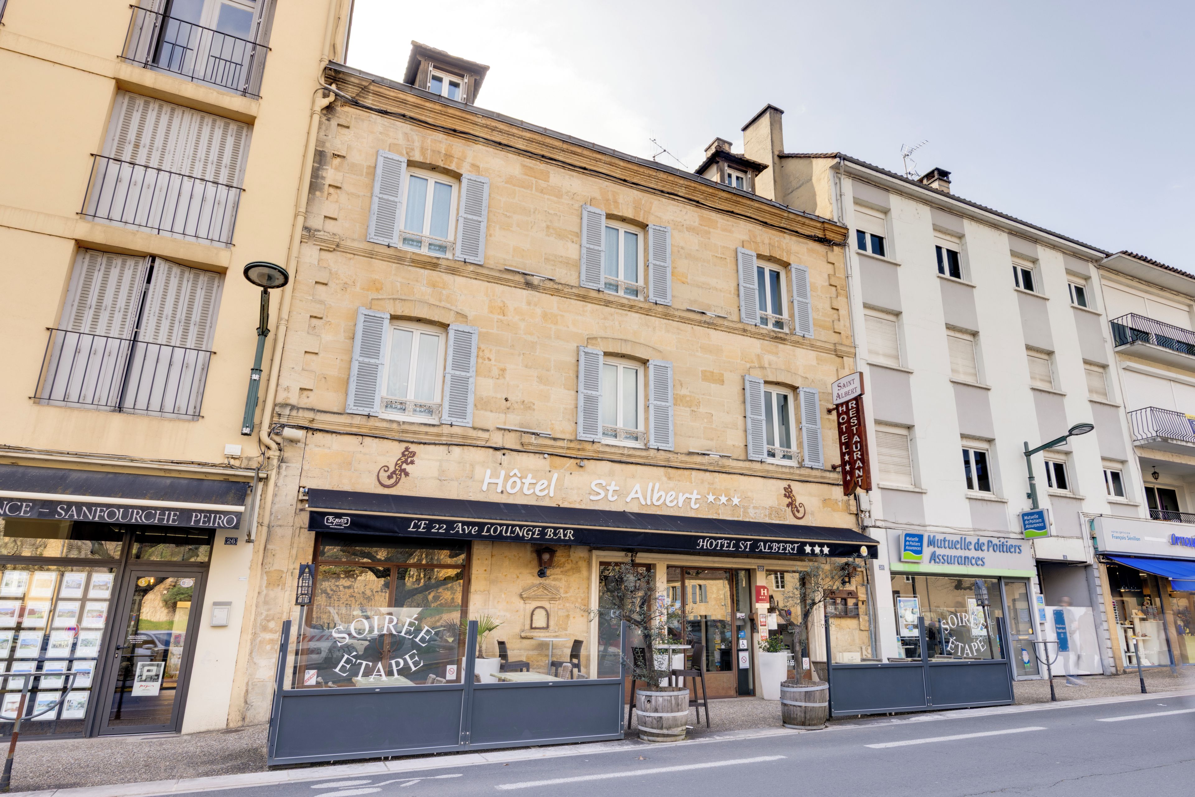 Un hôtel avec une enseigne indiquant « Hôtel Saint-Albert » et une autre indiquant « L’E 22 Ave, bar-salon ».