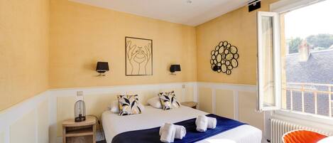 Habitación de hotel con una cama grande, una mesita de noche, una lámpara, una obra de arte en la pared y una ventana con vistas.