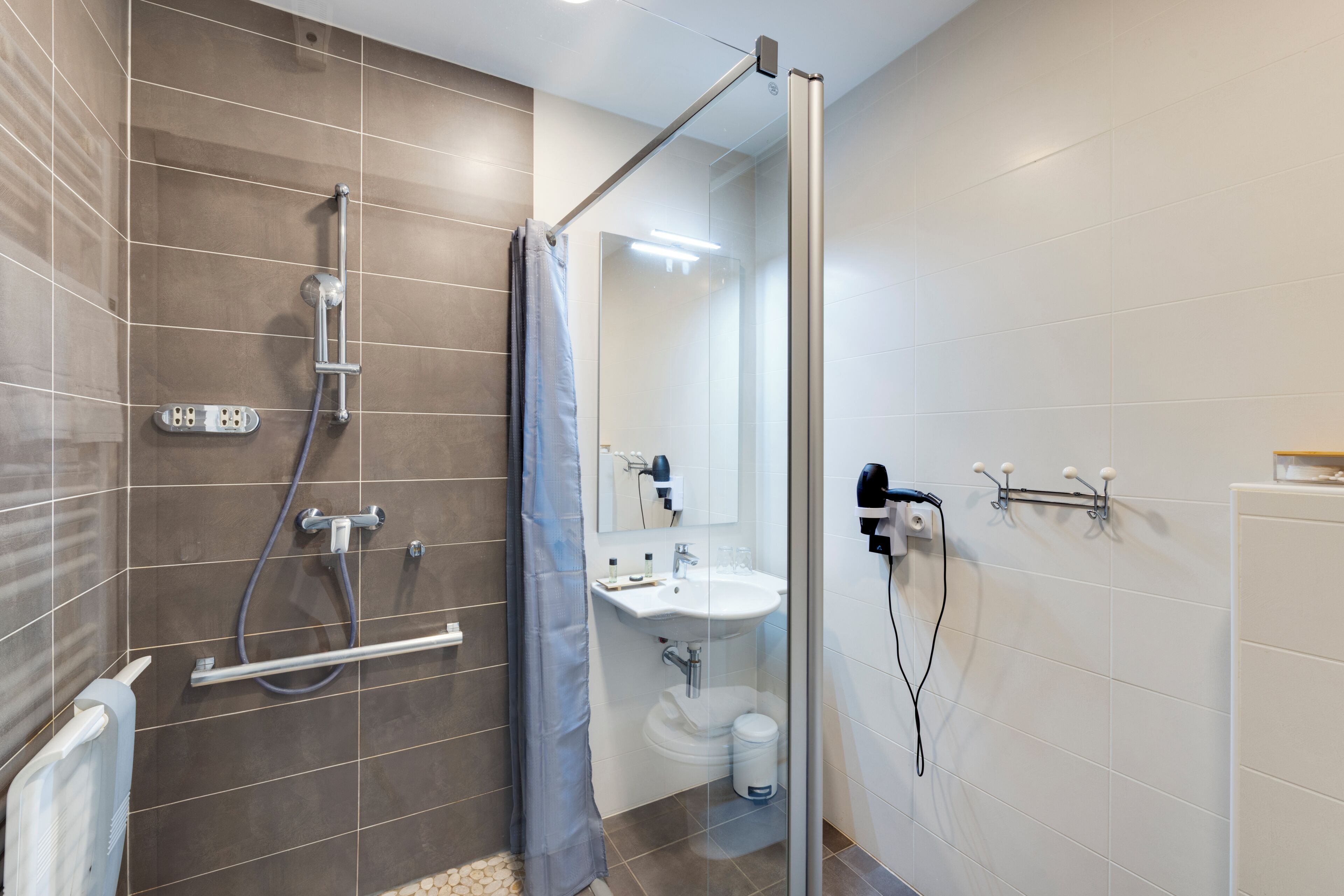 Ein modernes Badezimmer mit Duschkabine aus Glas, einem weißen Waschbecken und einem Spiegel.