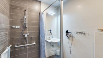Un baño moderno con cabina de ducha de vidrio, un lavabo blanco y un espejo.