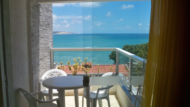 A balcony with a view of the sea, a table, and two chairs. - Aparthotel Margherita (Natal)