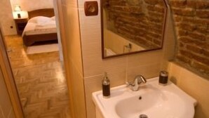 Un baño con un lavamanos blanco, un espejo y una pared de ladrillo.