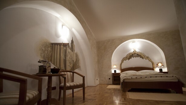 Un dormitorio con una cama de madera, dos lámparas de noche, una silla y una mesa.