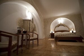 A bedroom with a wooden bed, two bedside lamps, a chair, and a table. - Casa Albert (Brasov)