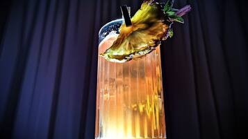 A clear glass with a decorative rim, filled with a golden liquid, and a garnish on the rim.