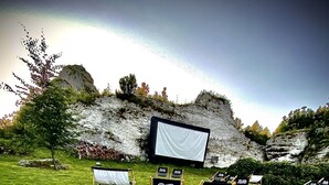 An outdoor movie screening area with a large screen, several seating areas, and a snack table with popcorn. - Poziom 511 Jura Wellness Hotel & Spa (Ogrodzieniec)
