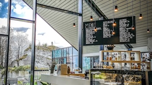 A modern cafe with a menu board, seating area, and a view of the outdoors. - Poziom 511 Jura Wellness Hotel & Spa (Ogrodzieniec)