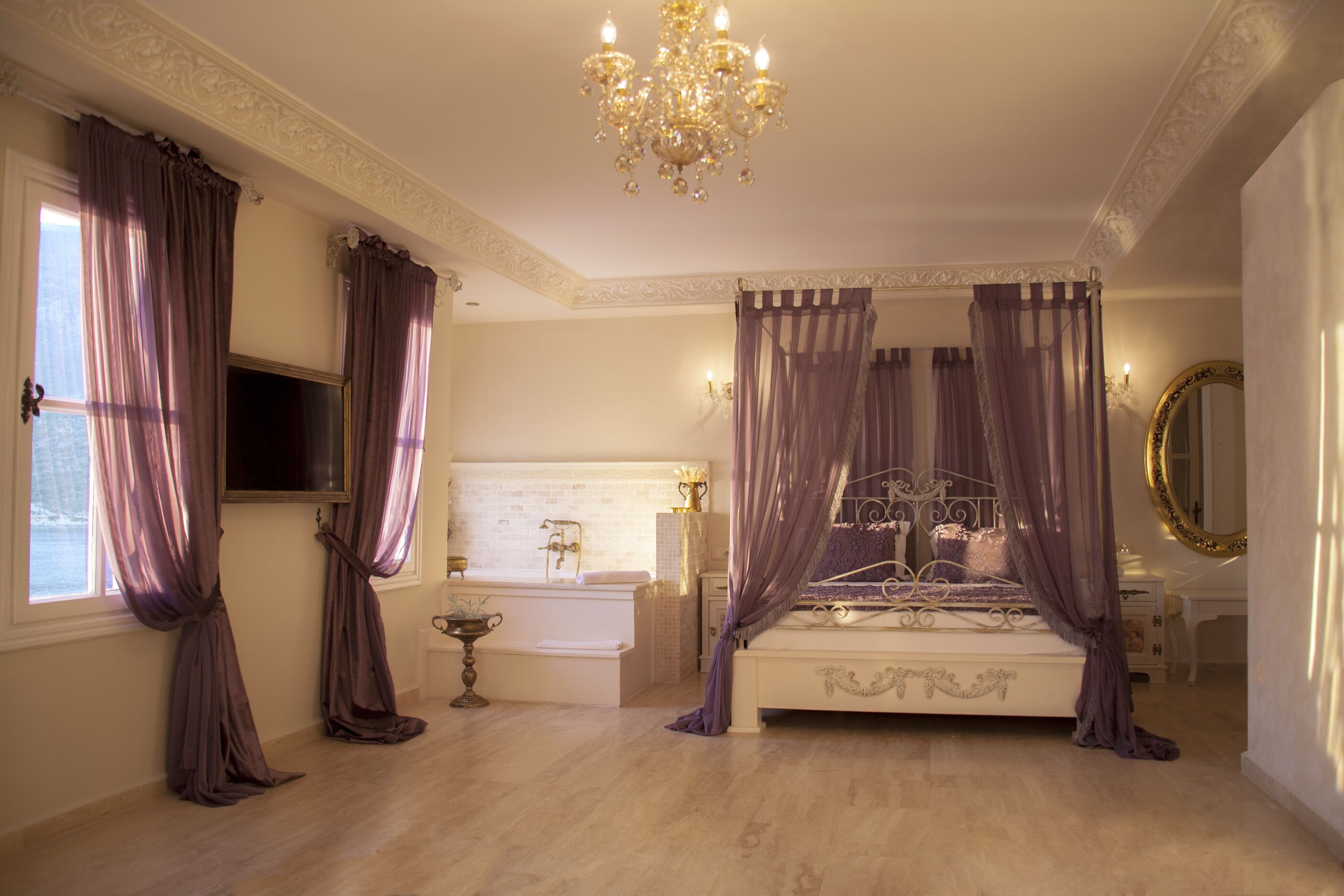 Un dormitorio con cama con dosel, un candelabro, un espejo grande y una bañera.
