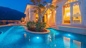 A luxurious pool area with a stone building, a palm tree, and a mountain in the background. - Lukka Exclusive Hotel - Adult Only +12 (Kas)
