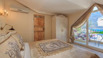 Een slaapkamer met een groot bed, een houten garderobe, een raam met gordijnen en een balkon met bloemen.