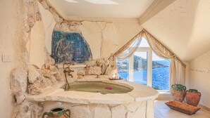 A stone bathtub with a view of the sea, a stone wall, and a window with curtains. - Lukka Exclusive Hotel - Adult Only +12 (Kas)