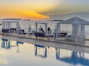 A poolside area with white canopies and purple cushions, overlooking a calm body of water during sunset. - Lukka Exclusive Hotel - Adult Only +12 (Kas)