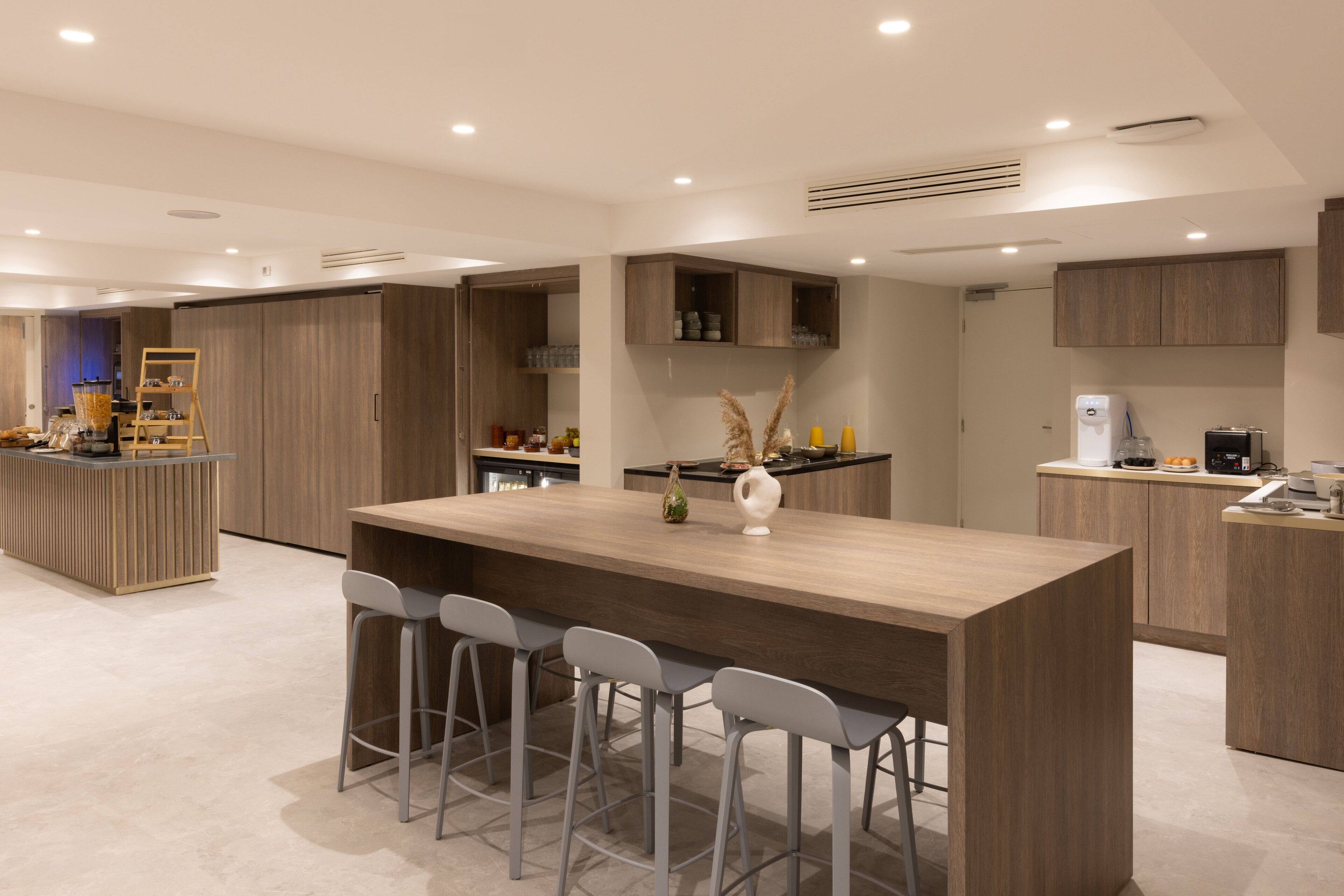 A modern kitchen with a central island, bar stools, and built-in cabinets.