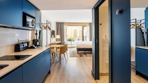Una habitación de hotel moderna con kitchenette, comedor y una cama grande.