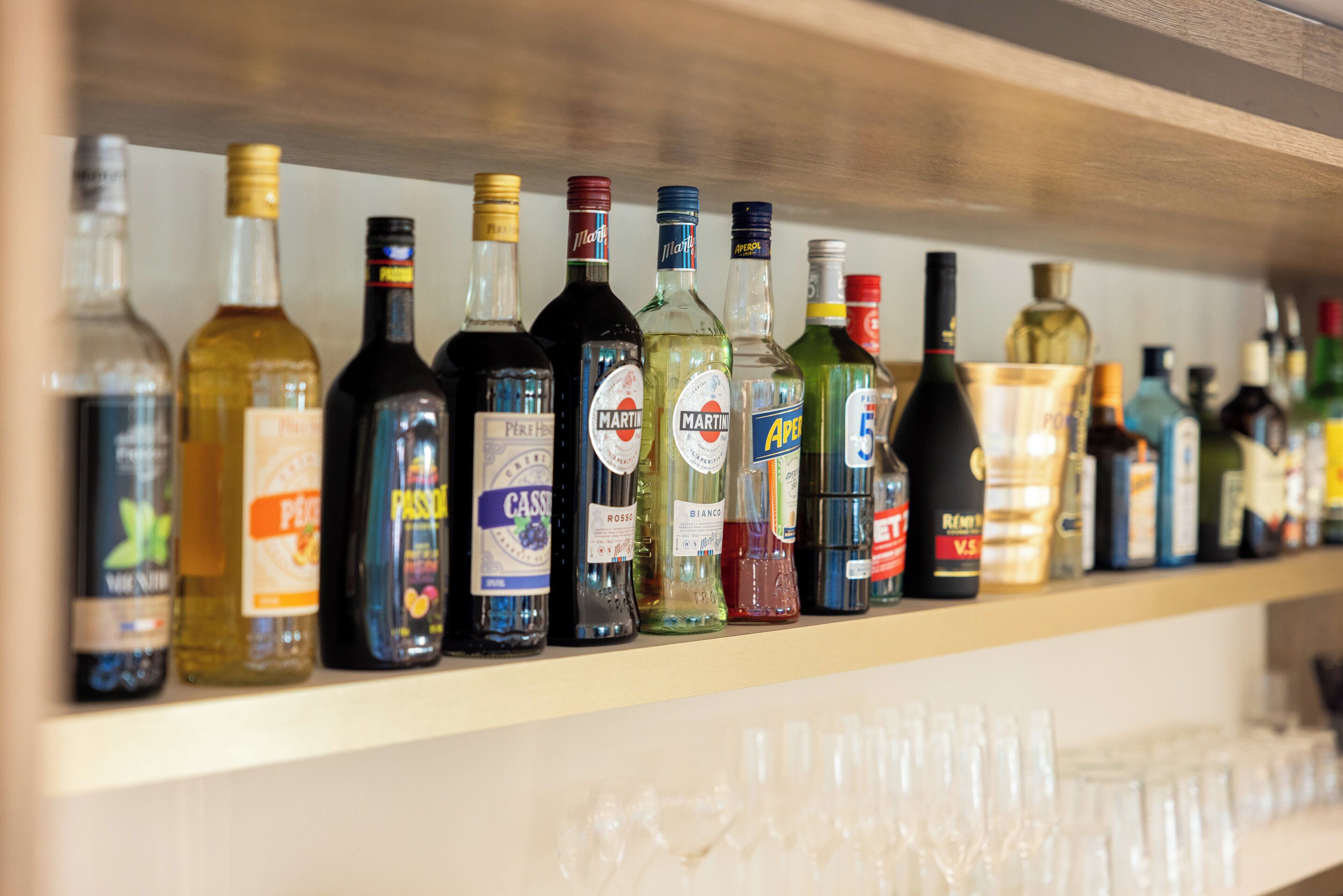A shelf with various liquor bottles and glasses.