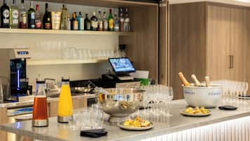 A bar area with a variety of liquor bottles, a cocktail shaker, glasses, and a bowl with champagne.