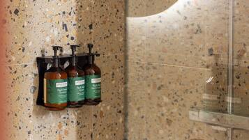 Un baño con pared de azulejos veteados y cabina de ducha de vidrio.