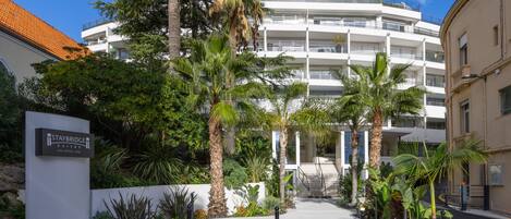 A hotel entrance with a sign for Staybridge Suites, a palm tree-lined pathway, and a multi-story building in the background.