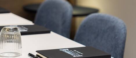 A conference table with a notebook, pen, and glass.