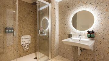 Een moderne badkamer met een douchecabine van glas, een wit wastafelmeubel en een grote spiegel.