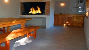 Una mesa de madera con bancos en una habitación con suelo de baldosas y una chimenea.