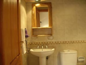 A bathroom with a wooden door, a white sink, a toilet, and a mirror above the sink. - Apart Hotel El Viejo Ciprés (San Carlos de Bariloche)