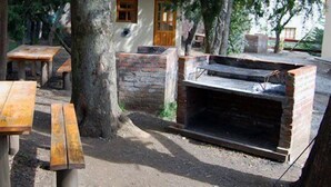 Un espacio de estar al aire libre de estilo rústico con mesas de madera y una barbacoa de ladrillo.