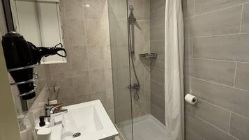 Une salle de bain moderne avec une douche à parois de verre, un lavabo blanc et des toilettes.