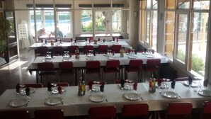 Un restaurante con varias mesas dispuestas para comer, ventanas amplias y un ventilador de techo.