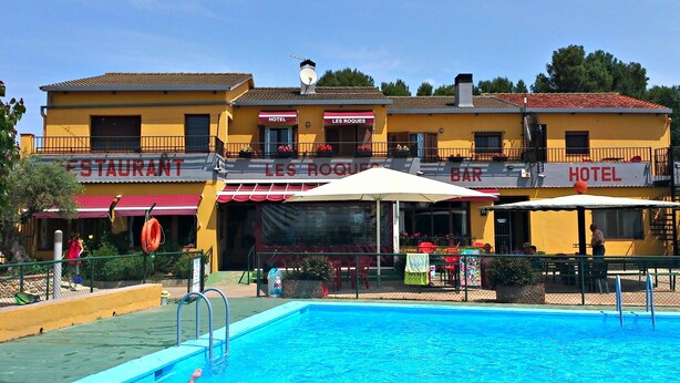 Un hotel con piscina, mobiliario exterior y restaurante.