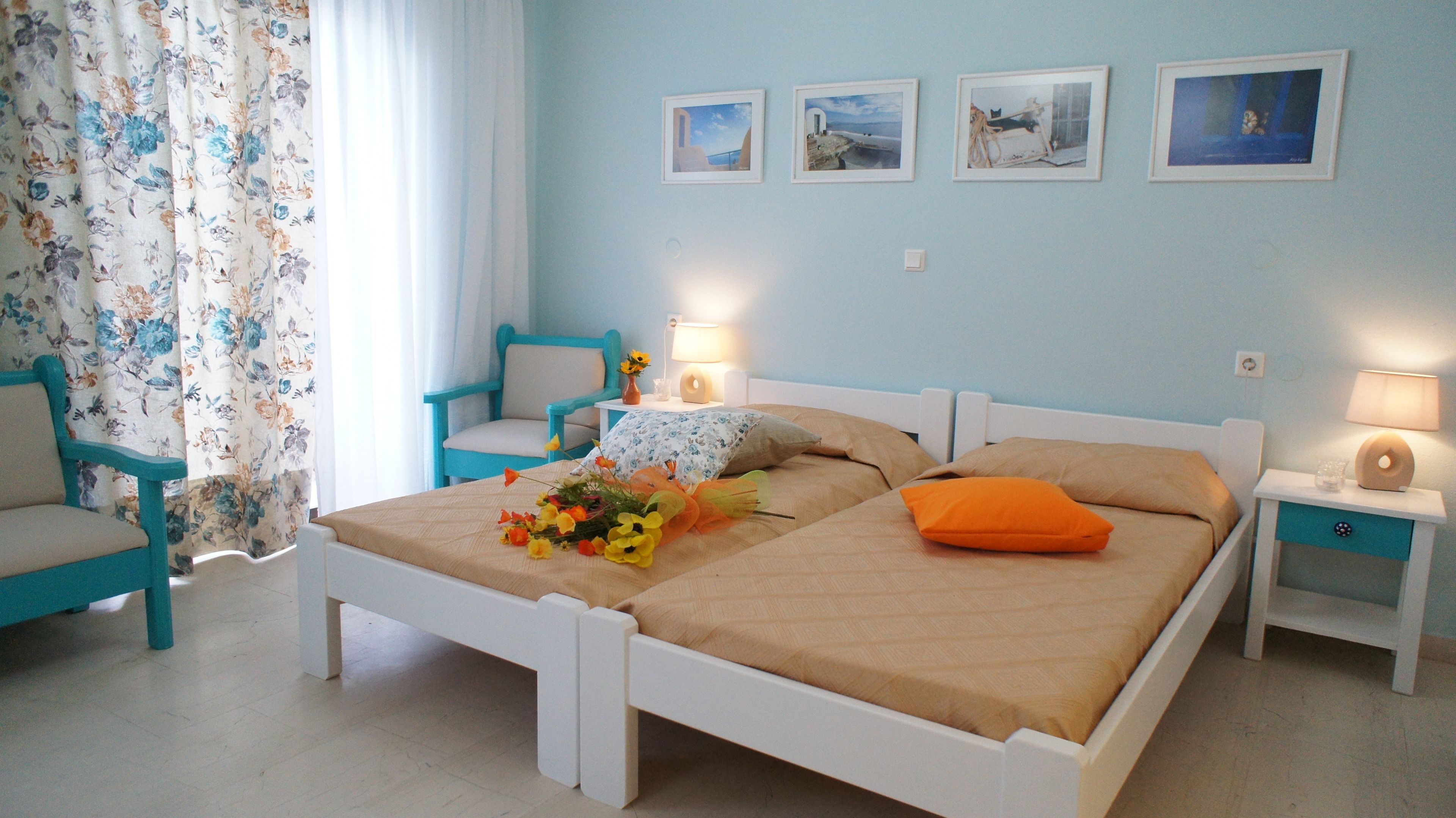 A bedroom with a bed, two nightstands, a chair, a lamp, and floral curtains.