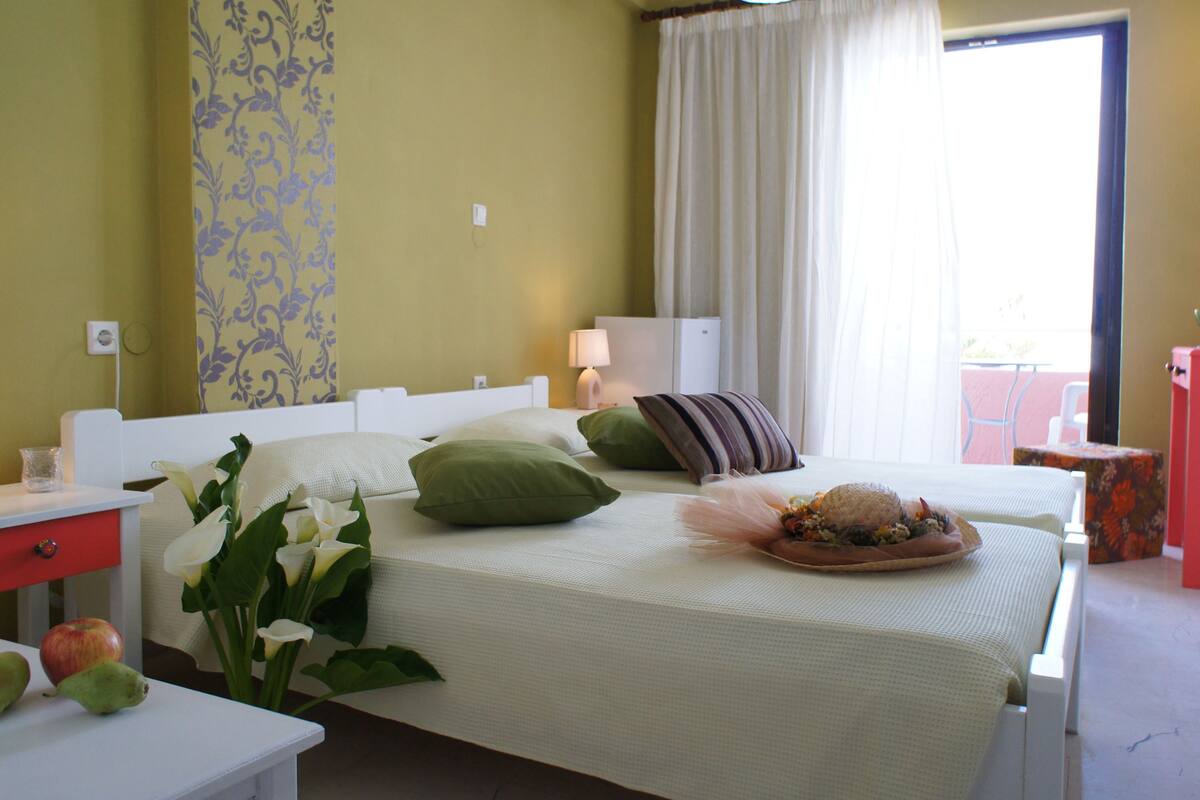 A hotel room with a bed, bedside tables, a nightstand, a lamp, a window with curtains, and a view of the outside.