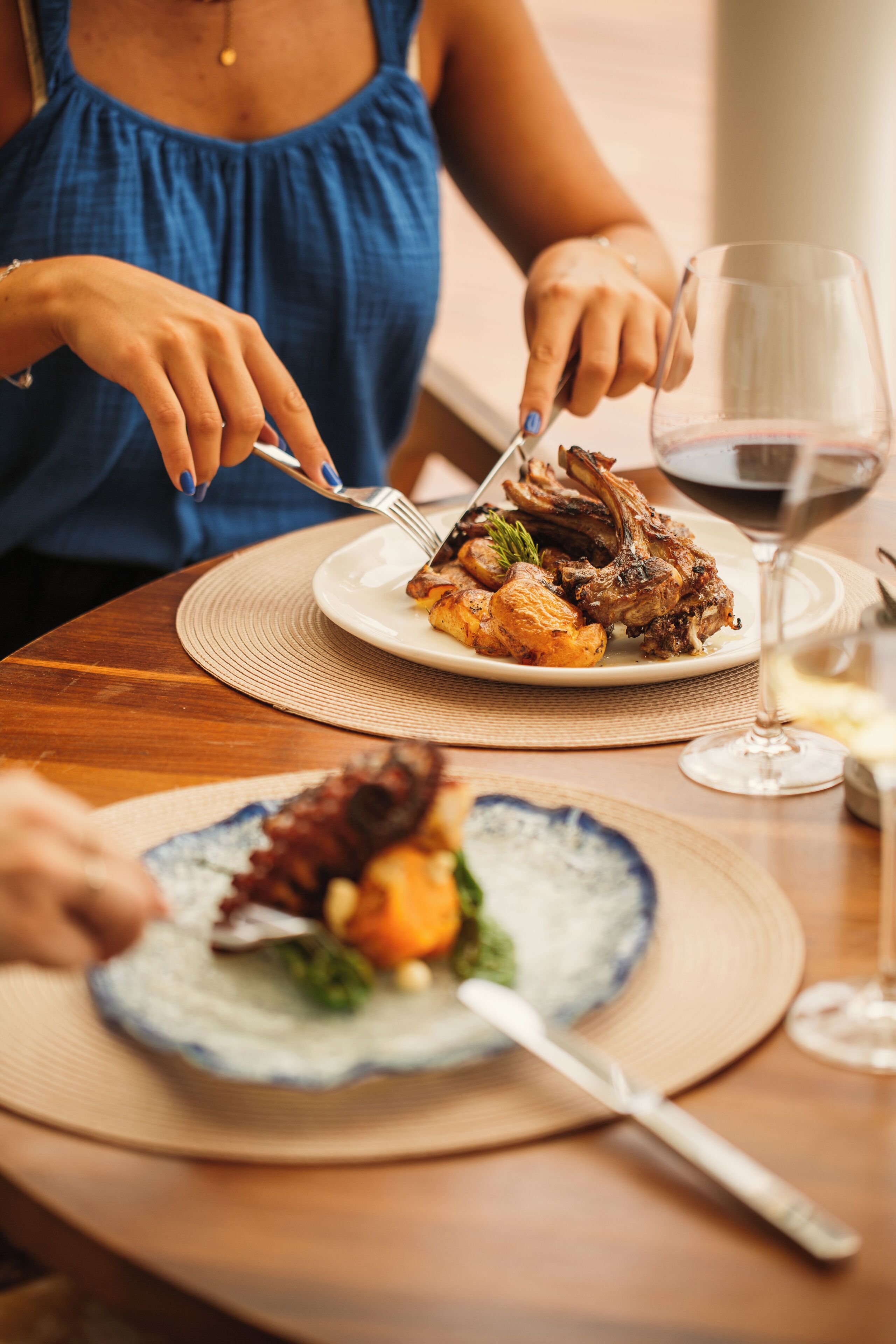 A dining table with a plate of food and a wine glass.