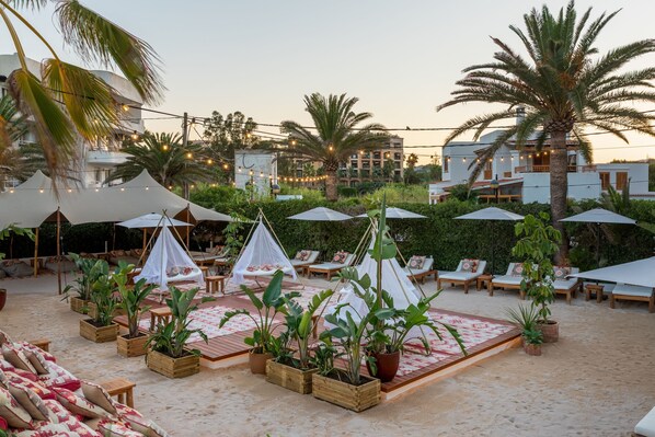 A beachside resort with tents, lounge chairs, and potted plants. - Hotel Riomar Ibiza, A Tribute Portfolio Hotel (Santa Eulalia del Rio)